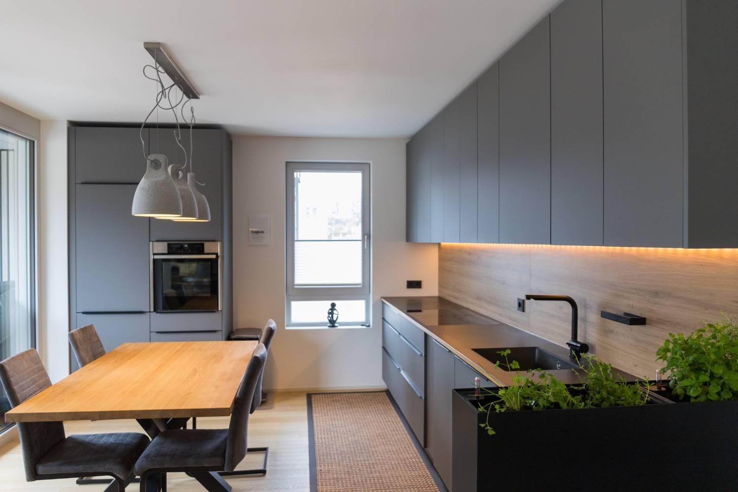 Nahaufnahme einer modernen Küche in grau mit eingelassener Spüle und eingelassenem Kochfeld